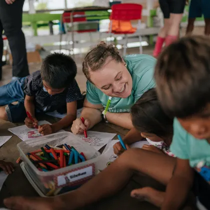 Luciene deitada no chão colorindo desenhos com crianças