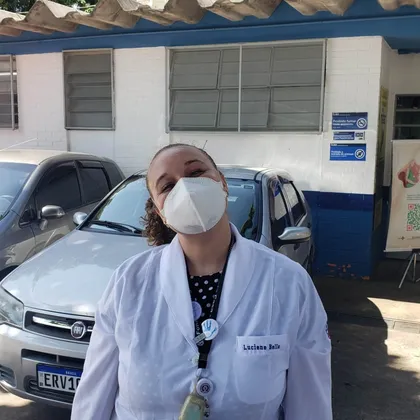 Luciene de jaleco em frente à placa da UBS
