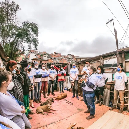 Roda de voluntários e moradores sobre a plataforma de uma casa em construção
