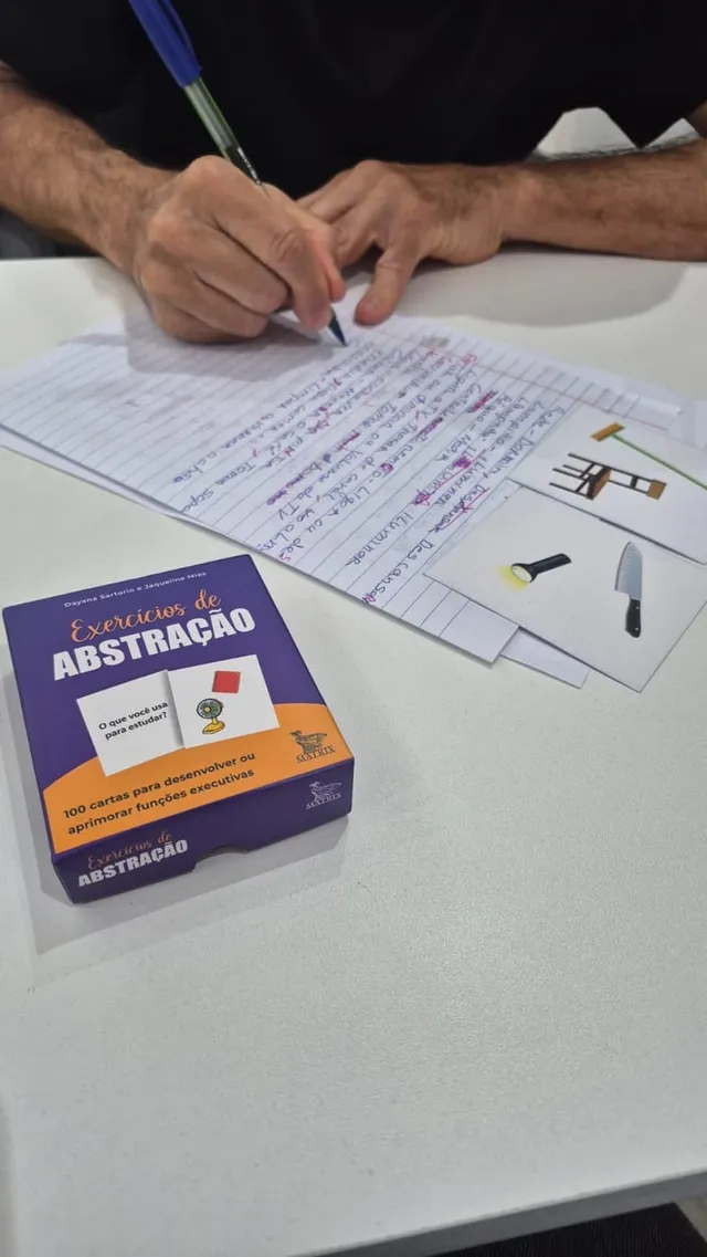 Paciente escrevendo a função de objetos ao lado de cartas ilustradas